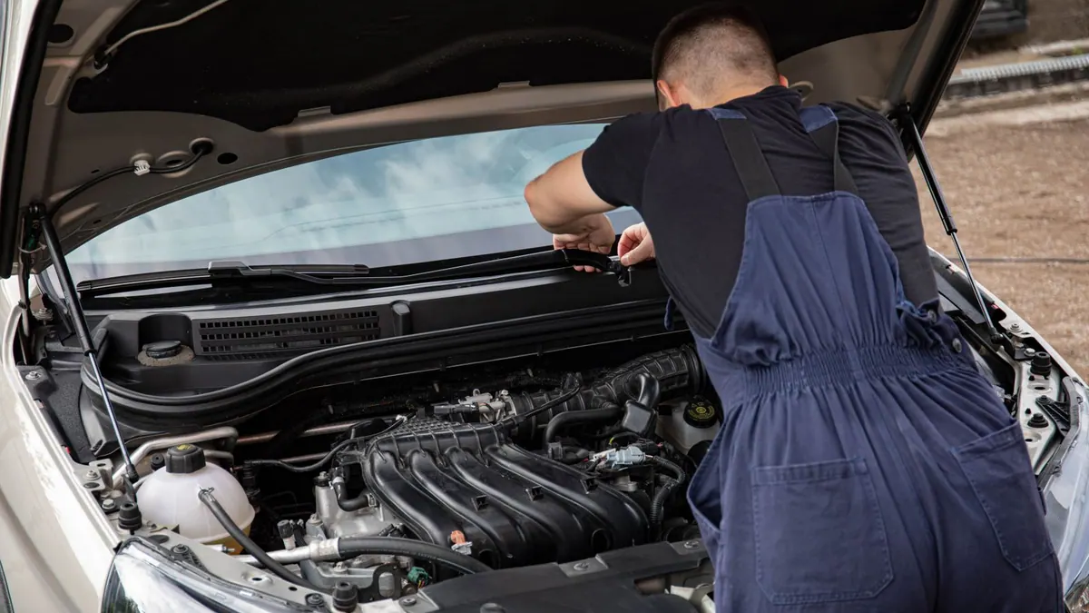 Mécanicien en bleu de travail réparant un moteur en extérieur